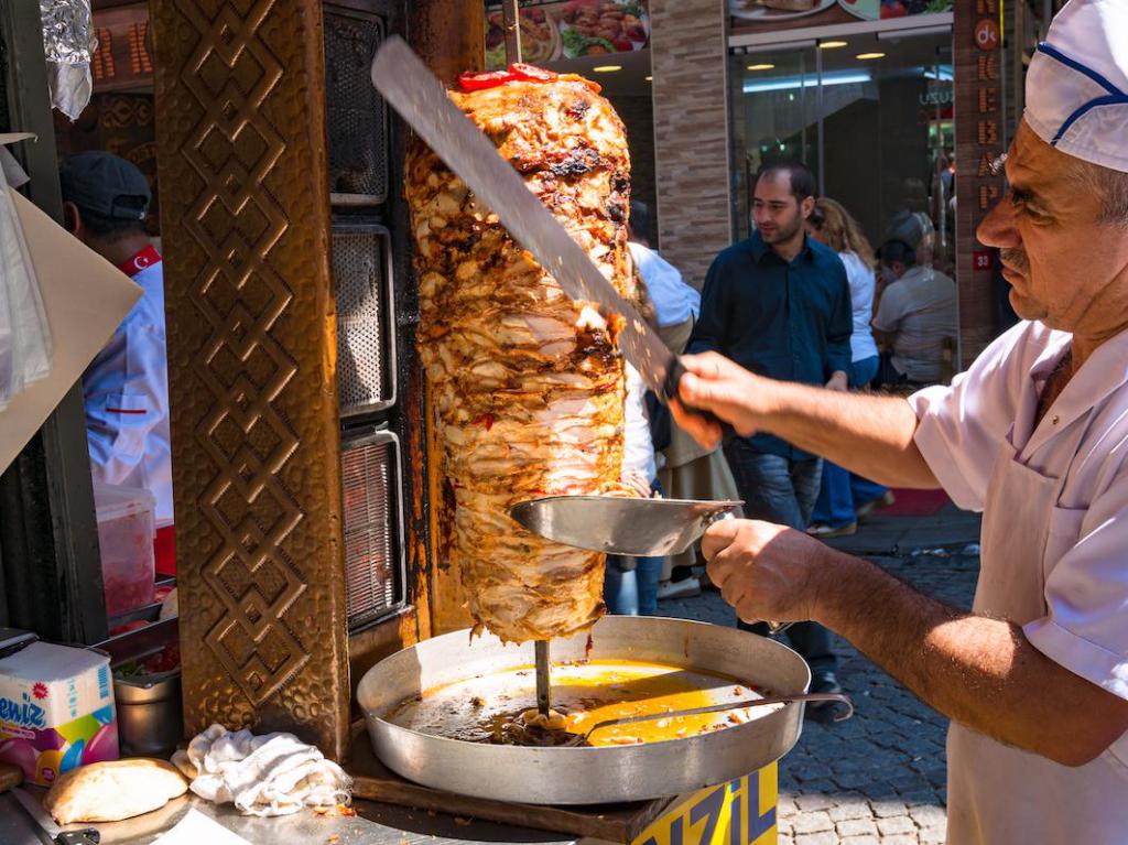 Мужчина режит мясо на шаурму