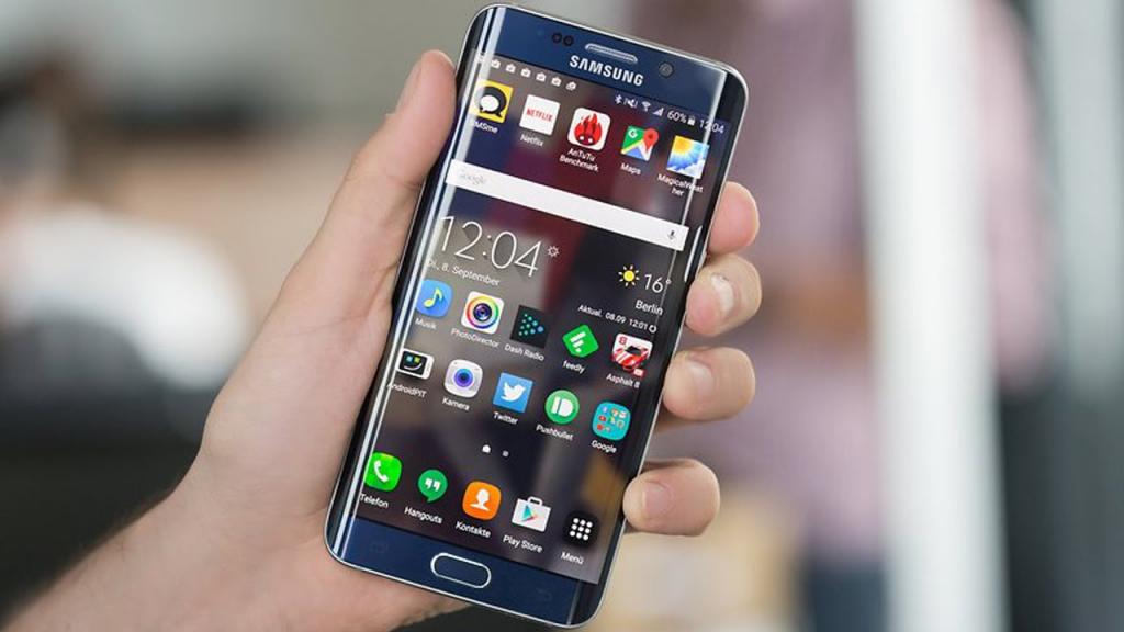 Человек держит в руках включенный смартфон.